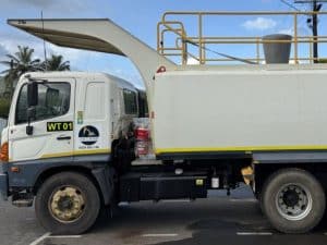 A white water truck with a chute and yellow railing, parked on a road. Water truck rental duration varies by need.
